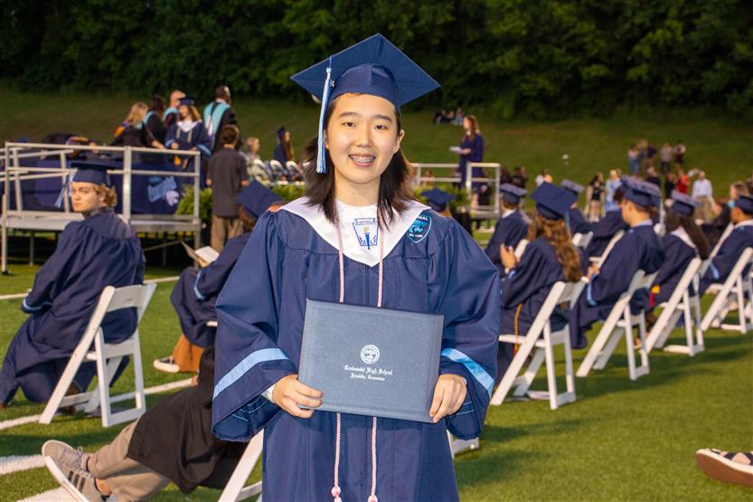 Students graduate outside on a football field